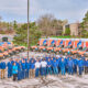 People in blue uniforms stand in a parking lot surrounded by orange and blue heating and cooling vans. Trees and a building frame this typical scene from Milwaukee.